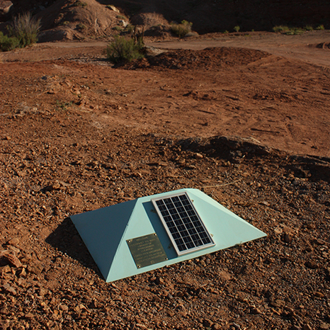 A sea-foam green pyramid with a solar panel sits on top of travertine rock deposited by a geyser.