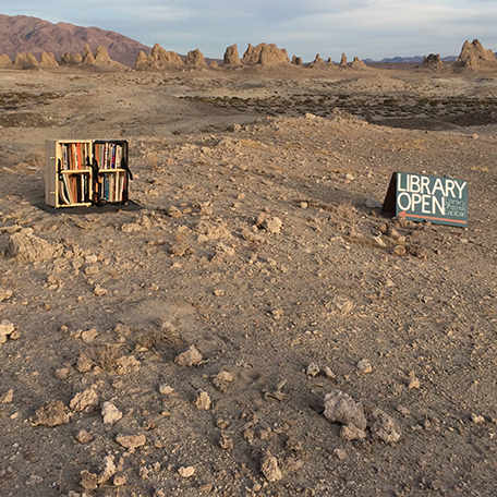 A library bookshelf in a desert landscape with tufa towers in the background.