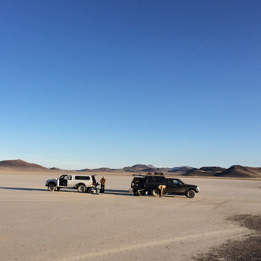 A circle of pickup trucks in the middle of a dry lakebed.