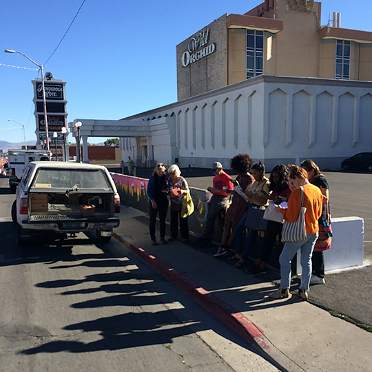 Readers peruse books standing on the street in front of a topless dance bar.
